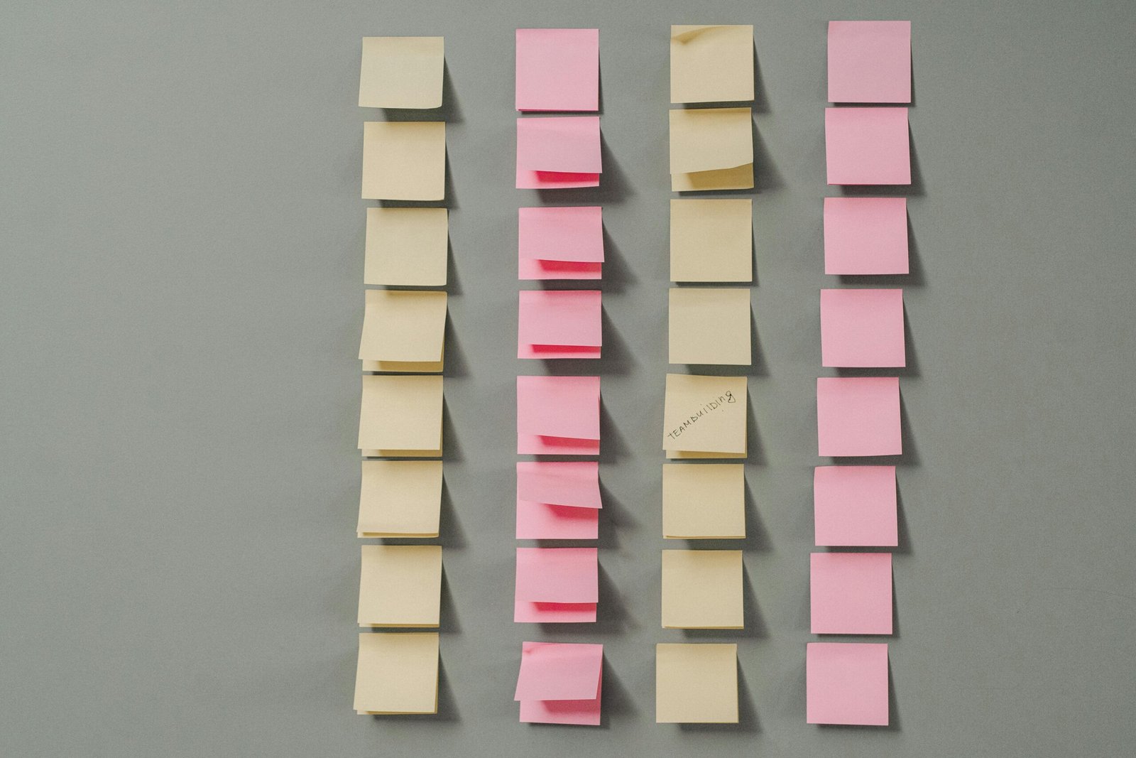 Rows of pink and yellow sticky notes on a gray background, ideal for planning concepts.